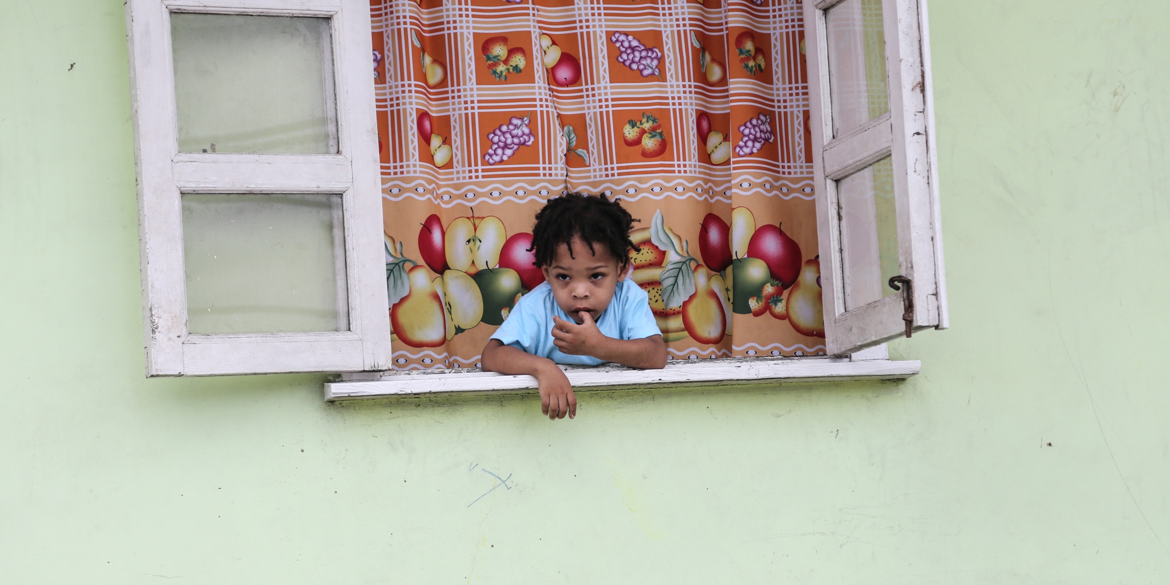 A child looks outside his window in Roseau, capital of Dominica. Credit: UNICEF/UN0126542/Moreno Gonzalez
