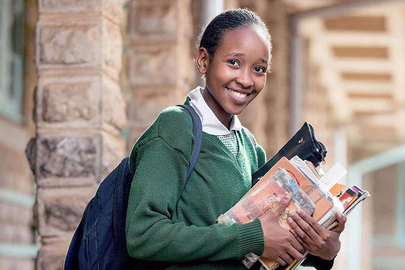 Une élève tenant son matériel scolaire entre ses bras. Crédit : GPE/Kelley Lynch 